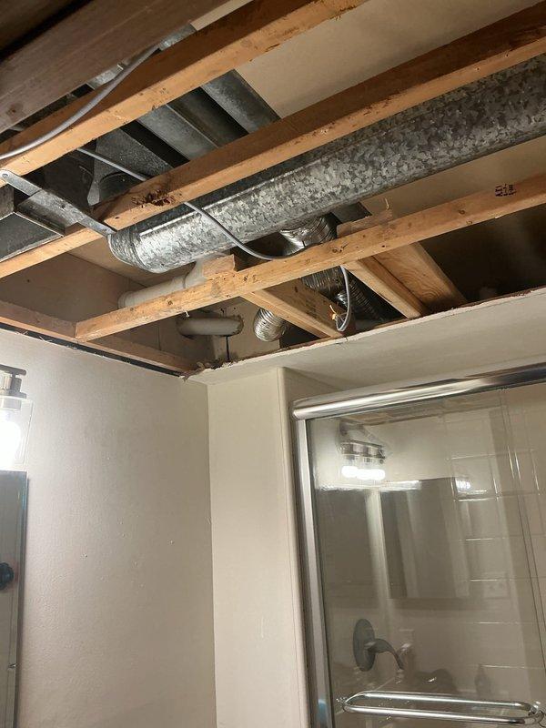 Responded to service call for water leak from air conditioning unit located in first-floor utility closet. Upon inspection, identified condensate drainage issue in the HVAC system's ductwork and plumbing connections visible in the exposed ceiling area above bathroom. Cleared condensate line obstruction, verified proper drainage flow, and confirmed all ductwork connections were secure with no additional moisture present. System tested and operating normally with no further leakage detected.