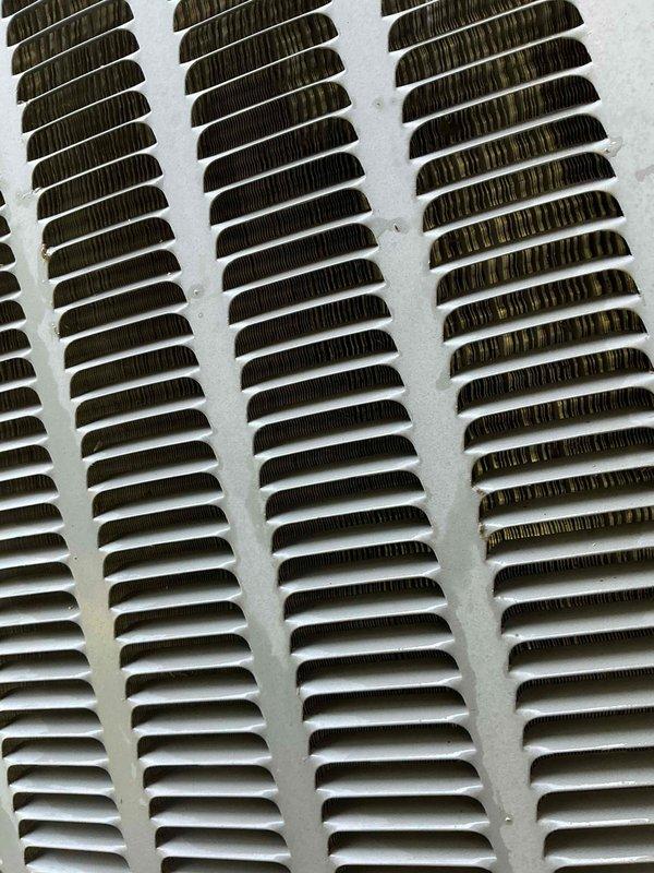 Responded to service call for air conditioning system not blowing cold enough air. Performed diagnostic testing on 10-year-old unit located in basement at ground level. Used digital multimeter to measure electrical readings and system performance, recording voltage at 35.86V. Inspected return air grille showing dust accumulation on louvers, indicating restricted airflow affecting cooling efficiency.