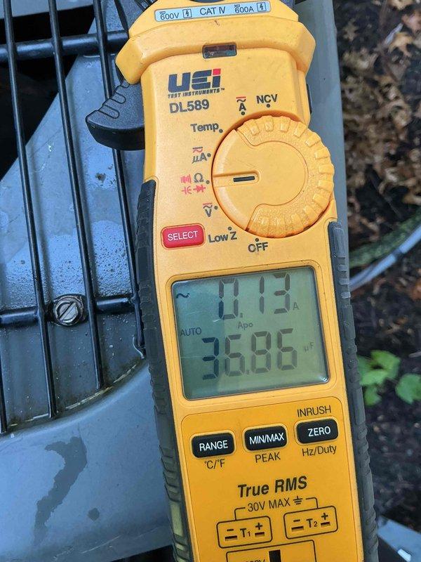 Responded to service call for air conditioning system not blowing cold enough air. Performed diagnostic testing on 10-year-old unit located in basement at ground level. Used digital multimeter to measure electrical readings and system performance, recording voltage at 35.86V. Inspected return air grille showing dust accumulation on louvers, indicating restricted airflow affecting cooling efficiency.