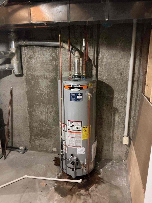 Installed a 50-gallon tall gas water heater in basement utility area against concrete block wall. Connected copper supply and distribution piping to overhead plumbing system, installed required safety valves and fittings, and ensured proper venting configuration. Applied required plumbing identification sticker and completed installation per permit requirements.