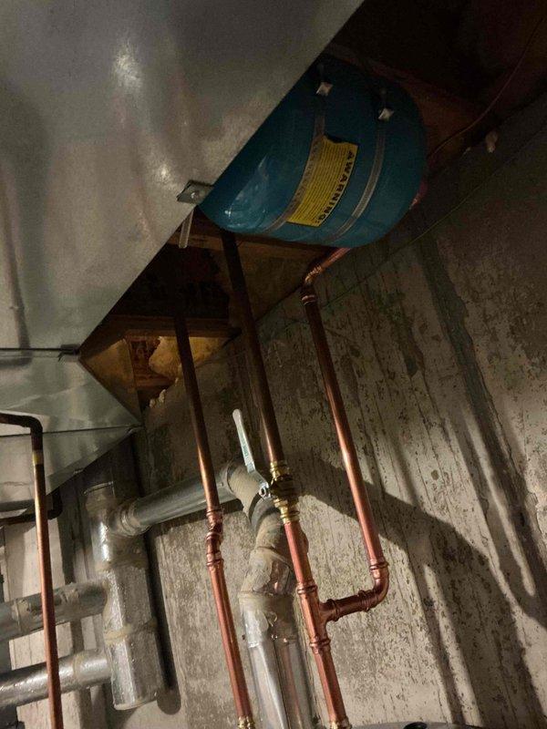 Installed a 50-gallon tall gas water heater in basement utility area against concrete block wall. Connected copper supply and distribution piping to overhead plumbing system, installed required safety valves and fittings, and ensured proper venting configuration. Applied required plumbing identification sticker and completed installation per permit requirements.