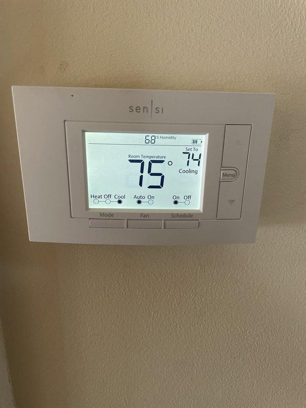 Responded to no cooling complaint on second floor. Upon arrival, found thermostat set to 74°F with current temperature reading 75°F in cooling mode, with humidity at 68%. Inspected attic-mounted air handler unit and associated ductwork system. Verified equipment operation, checked refrigerant levels, and examined condensate drainage system with white PVC piping. Photographed thermostat settings and air handler installation for service records. System restored to proper cooling operation, resolving second floor temperature issue.