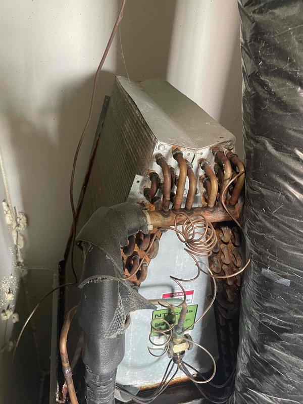 Completed comprehensive HVAC tune-up on 6-year-old residential air conditioning system with air handler located in basement utility space. Performed standard maintenance protocol including inspection of evaporator coil assembly, refrigerant lines, electrical connections, and ductwork connections. Noted significant oxidation and corrosion present on exposed copper refrigerant tubing and coil connections throughout the system, which is typical for units of this age but warrants monitoring for potential future refrigerant leaks. Verified proper operation of condensate drain system and inspected drain pan for functionality. Assessed compact vertical installation configuration with heat pump components and confirmed all mechanical connections remain secure despite visible weathering on copper components. Provided estimate for whole-house air purification system installation as requested.