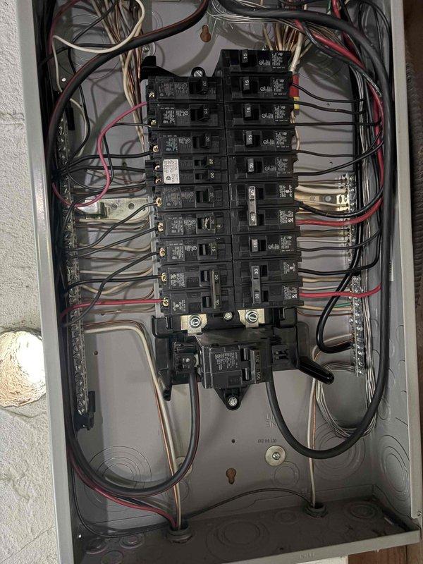 # Electrical Panel Code Compliance Correction

Responded to failed electrical inspection requiring panel code compliance upgrades. Upon arrival, assessed exterior Milbank service entrance equipment and interior main distribution panel. Exterior evaluation revealed PVC conduit installation with proper mounting and junction box connections on brick facade. 

Interior panel inspection identified multiple code violations beyond simple circuit identification issues. Panel contained mixed-age wiring installations with varying insulation types, improper wire routing, and inadequate labeling throughout the breaker array. Conducted comprehensive evaluation of all branch circuits, main breakers, neutral bus connections, and grounding system integrity.

Provided detailed estimate for necessary corrections to bring electrical panel installation into full code compliance, including proper circuit identification, wire management improvements, and any required hardware upgrades to meet current electr