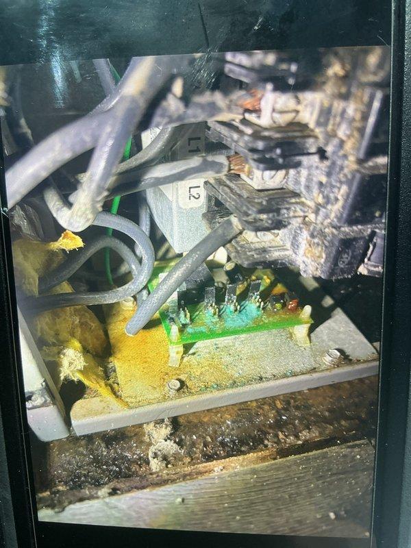 Responded to no cooling call on 1-year-old outdoor unit. Upon arrival, found system completely inoperative with no airflow from indoor blower. Inspected electrical panel and discovered significant deterioration in control box with heavy dust and debris accumulation affecting electrical connections. Terminal block showed signs of age with multiple loose wire connections at brass terminals. Capacitors and electrical components displayed corrosion and environmental damage. Identified failed control board connections and compromised wiring integrity due to moisture intrusion, evidenced by severe staining on surrounding concrete surfaces. Cleaned electrical connections, secured all terminal block wiring, and tested system operation. Advised property owner of need for future electrical enclosure maintenance to prevent recurring issues. System restored to operational status with proper airflow and cooling function confirmed.