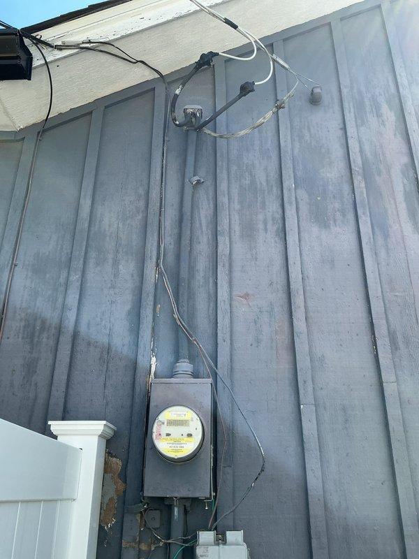 Conducted on-site evaluation for standby generator installation at residential property. Assessed existing electrical service entrance, metering equipment, and utility connection points mounted on exterior wall with metal siding. Documented current electrical infrastructure including meter enclosure, service conduits, and overhead service wires to determine compatibility and requirements for generator integration with main electrical panel.