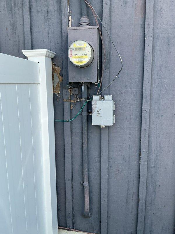 Conducted on-site evaluation for standby generator installation at residential property. Assessed existing electrical service entrance, metering equipment, and utility connection points mounted on exterior wall with metal siding. Documented current electrical infrastructure including meter enclosure, service conduits, and overhead service wires to determine compatibility and requirements for generator integration with main electrical panel.