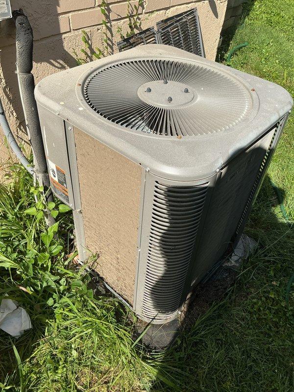 Responded to service call for AC unit not cooling at residential property. Upon arrival, performed visual inspection of outdoor condenser unit, which showed signs of weathering and environmental exposure consistent with 10-year-old equipment. Documented unit condition with photographs showing significant dirt accumulation on cabinet surfaces, water staining on side panels, and overgrown vegetation around base restricting proper airflow. Cleared debris and vegetation from around unit perimeter to restore adequate clearance for ventilation. Inspected condenser coils through louvers and noted moderate dirt buildup affecting heat transfer efficiency. System operational assessment and diagnostic testing completed to identify cooling deficiency cause.