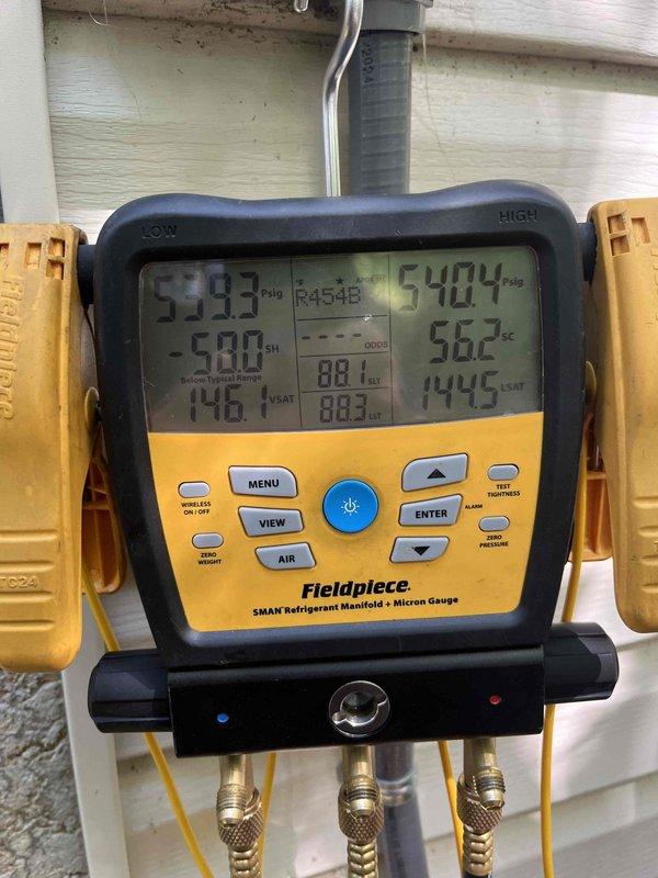 Continued leak search on residential AC system under first-year warranty that was not cooling. Connected refrigerant manifold gauges to measure system pressures and temperatures, recording readings of 533.3 PSIG suction and 540.4 PSIG discharge with corresponding temperatures. Inspected evaporator coil assembly which showed heavy dust and debris accumulation on A-frame coil surfaces that could restrict airflow and reduce cooling capacity. Previous service visit was interrupted due to weather conditions; completed diagnostic testing during this follow-up to identify source of cooling issue and potential refrigerant leak.