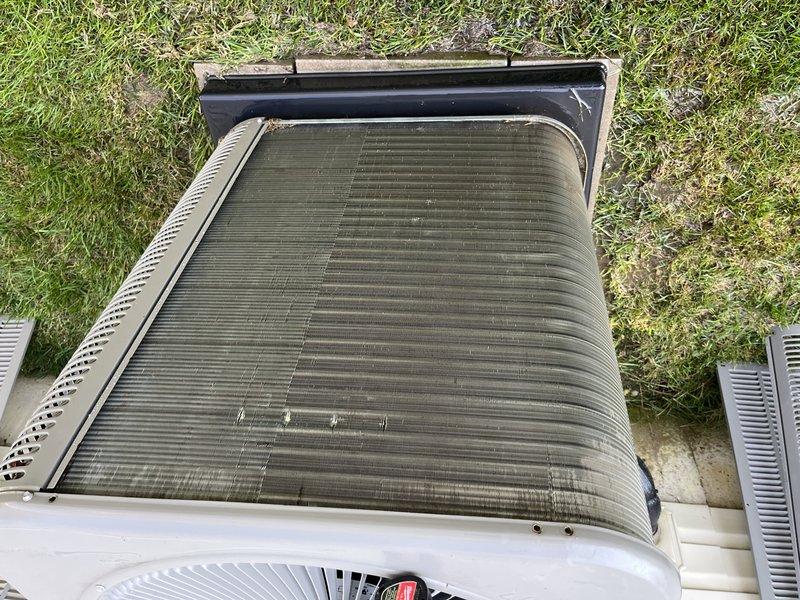Completed preventive maintenance tune-up on outdoor heat pump/air conditioning condenser unit. Upon arrival, noted significant accumulation of dirt, dust, and debris clogging the heat exchanger coil fins, which was restricting airflow and reducing system efficiency. Performed thorough cleaning of condenser coils to remove buildup between fins, inspected fan motor and blade operation, and verified proper unit function. System restored to optimal operating condition.