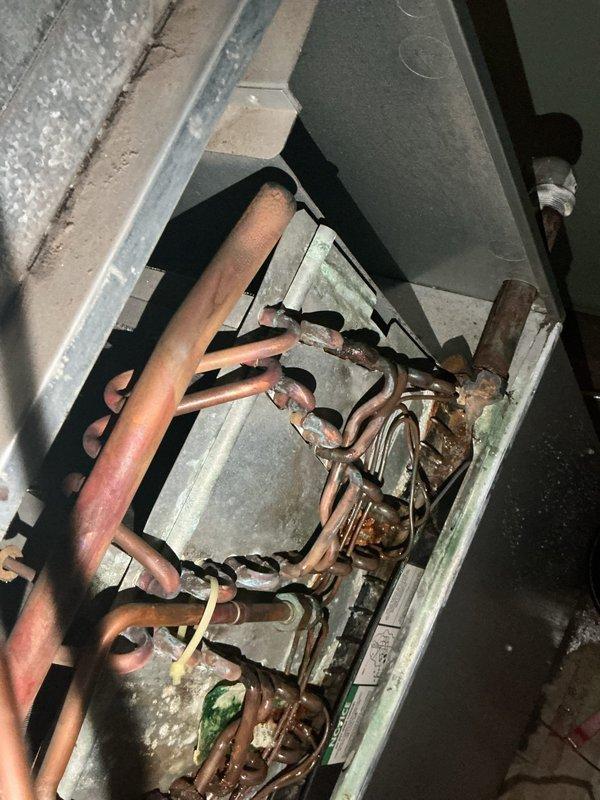Responded to report of water leaking from air conditioning unit in basement. Upon inspection, found broken condensation drain pan allowing water to overflow from the system. Observed extensive corrosion on copper refrigerant lines and significant deterioration of insulation, indicating prolonged moisture exposure on 10+ year old unit. Advised to shut off AC immediately and leave fan running to prevent further water damage until drain pan can be replaced and system properly evaluated for additional moisture-related damage.
