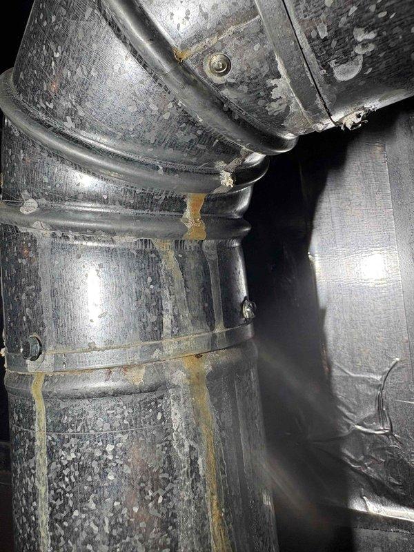 Responded to service call for AC unit leaking in basement. Upon inspection, discovered significant moisture accumulation on ductwork and evidence of condensation issues in confined mechanical space. Identified rust and corrosion on metal brackets and mounting hardware, along with visible water staining on insulation materials. Documented existing conditions of 10-year-old outdoor unit and associated ductwork system showing signs of age-related deterioration. Photographed affected areas including compromised insulation, condensation on reflective duct surfaces, and corroded fastening components for repair recommendations.