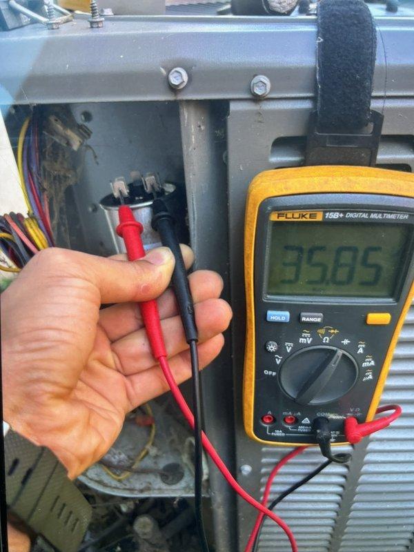 Responded to no cooling call on 15-year-old AC system with outdoor unit not running and thermostat displaying "waiting on equipment" message. Upon arrival, performed electrical diagnostics using digital multimeter to test voltage and continuity at outdoor unit's control panel. Identified failed dual run capacitor with reading of 35.05 microfarads, significantly below manufacturer specifications, preventing compressor and condenser fan motor from starting. Replaced defective capacitor with properly rated OEM replacement part, verified all electrical connections, and tested system operation. Unit successfully started with compressor and outdoor fan running at correct amperage, thermostat communication restored, and system cooling normally. Advised customer that 15-year-old system is nearing end of expected service life and recommended consideration of replacement options for improved efficiency and reliability.