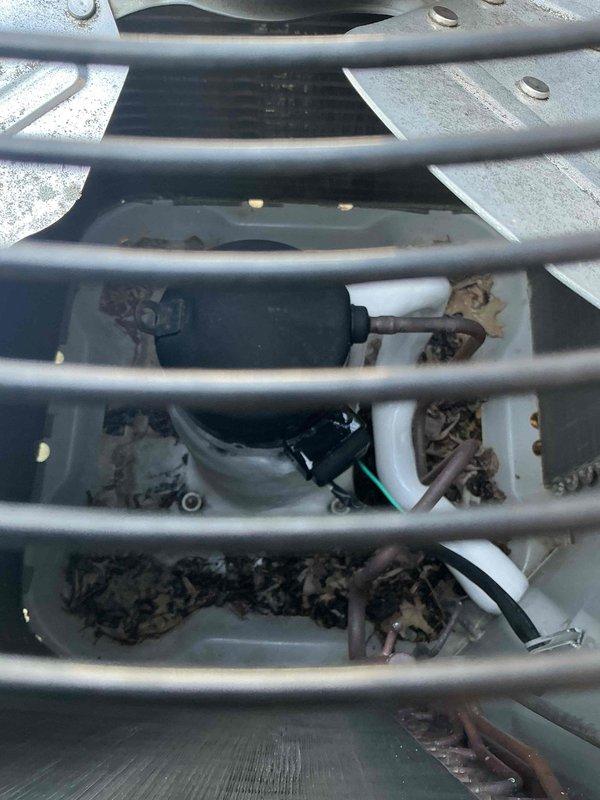 Responded to callback for air conditioning unit not cooling below 80 degrees. Upon arrival, inspected outdoor condensing unit and found accumulated debris beneath top grille restricting airflow to compressor compartment. Removed protective grating, cleared leaves and organic matter from unit interior, and verified all mechanical components operational. Unit tested successfully with proper airflow restored and cooling cycle functioning within normal parameters.