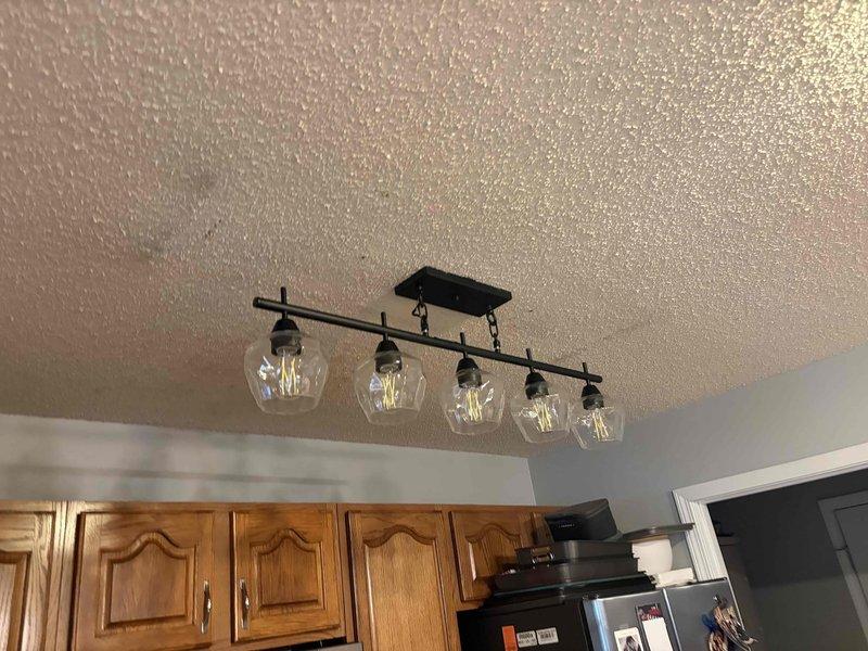 Responded to service call for multiple non-functional electrical outlets and performed lighting fixture upgrades. Troubleshot and repaired several outlets that had lost power, restoring functionality to the affected circuits. Upgraded existing lighting to fluorescent fixtures, including installation of flush-mount rectangular fluorescent fixture with white diffuser panel and bronze trim in one location, and installation of modern five-light industrial-style fixture with black metal frame and clear glass globe bulbs in kitchen area. All fixtures tested and confirmed operational upon completion.
