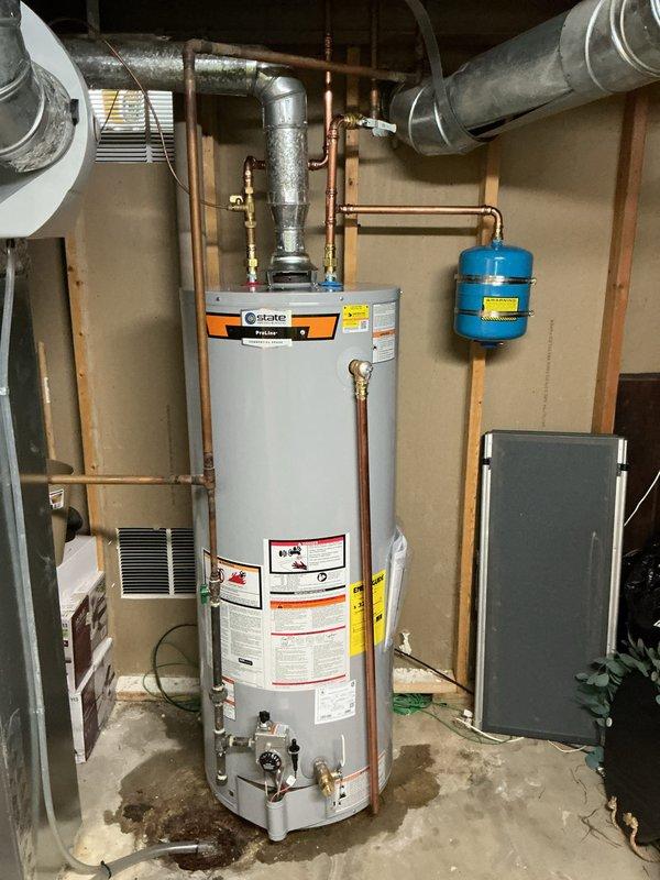 Installed 50-gallon tall gas water heater in residential utility room with complete plumbing connections including copper supply and discharge piping, brass fittings, and blue expansion tank. Applied required plumbing identification sticker per permit 26plu-16984 and verified all code compliance requirements were met for final inspection.