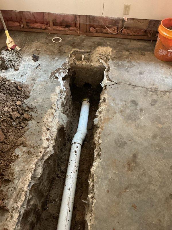 Completed plumbing permit 26-001638 involving the removal and replacement of existing cast iron drain piping with new PVC drainage system. Excavated concrete floor and trenched to access underground piping, then installed new white PVC drain lines to accommodate relocated tub drain for new shower base installation. Installed new shower valve assembly with copper supply lines run vertically through wall framing. All new piping was properly fitted, connected, and positioned according to code requirements to support the updated bathroom fixture layout.