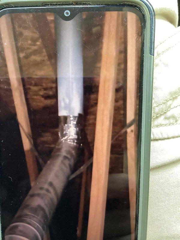 Completed follow-up repair service on HVAC system. Replaced defective flue pipe with proper elbow fitting in attic space to ensure correct venting configuration. Performed thorough cleaning of exterior Lennox condenser unit by hosing down coils and exterior surfaces to remove debris and improve system efficiency. Documented all completed work with photographs of the installed flue pipe assembly and cleaned condenser unit for service records.