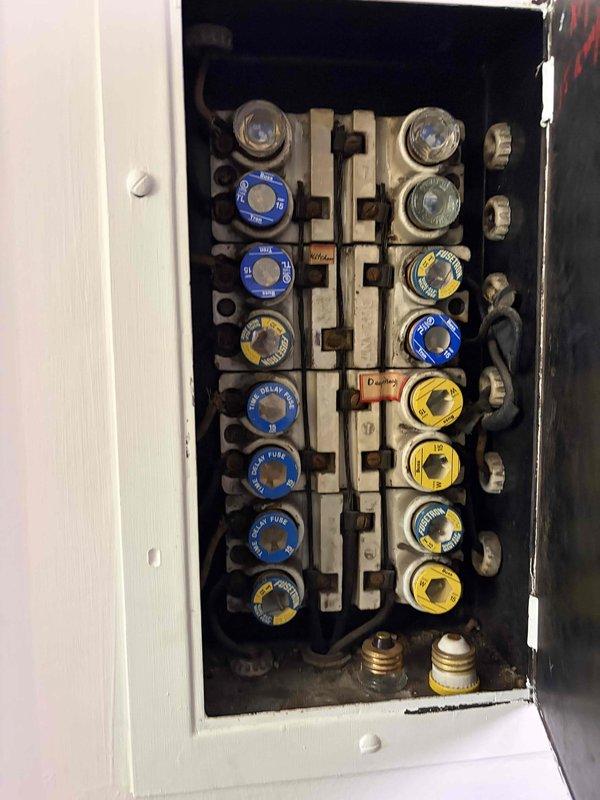 Completed comprehensive whole house electrical inspection of residential property. Evaluated exterior electrical service entrance, metering equipment, and weatherhead installation with conduit routing along exterior wall. Inspected main electrical panel containing older style screw-in fuse system with color-coded fuses (blue, yellow, and clear rings) and brass main disconnect fuses. Documented all findings with photographs for client records. System utilizes outdated fuse-based protection rather than modern circuit breakers, which was noted during inspection. All accessible electrical components, connections, and service equipment were visually examined for safety compliance and proper operation.