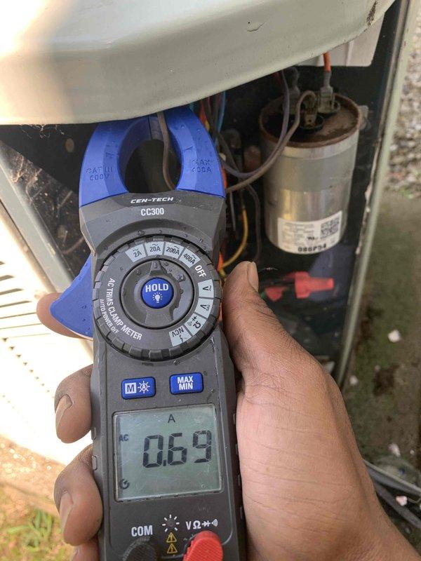 Completed preventive maintenance tune-up on outdoor condensing unit located on side of home. Performed comprehensive system diagnostics including electrical testing with clamp meter, which revealed normal amperage draw of 0.69 amps. Inspected capacitor and all electrical connections, verified proper component operation, and documented system performance with photos for service records.