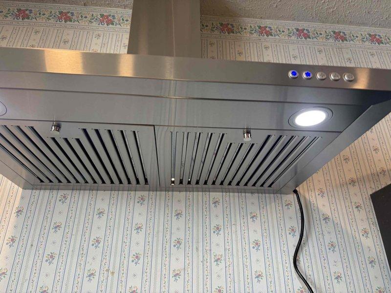 Returned to complete electrical installation for kitchen range hood as part of ongoing HVAC and lighting project. Completed wiring and power connection for stainless steel chimney-style range hood unit, ensuring proper electrical supply to ventilation system, LED lighting, and control panel. Verified all electrical connections were secure and hood controls functioning properly, including multi-speed fan settings and integrated lighting features. Installation completed successfully with unit fully operational.