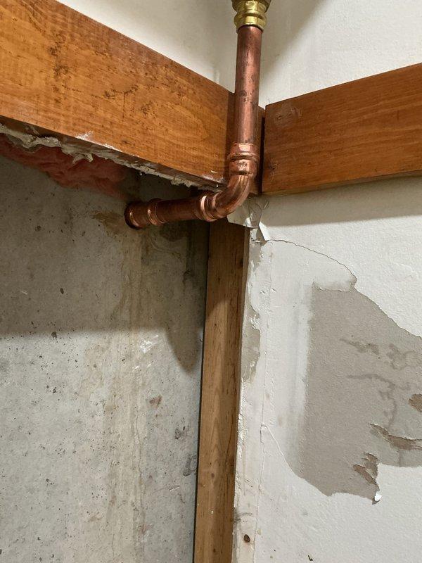 Responded to emergency water service repair requiring both interior and exterior excavation work. Accessed existing copper water service line through interior wall, exposing copper piping with brass fittings and elbow connections near structural floor joists. Excavated exterior trench to locate and repair underground water service line, removing soil layers to access damaged section. Completed necessary repairs to restore water service functionality and backfilled excavation upon completion.