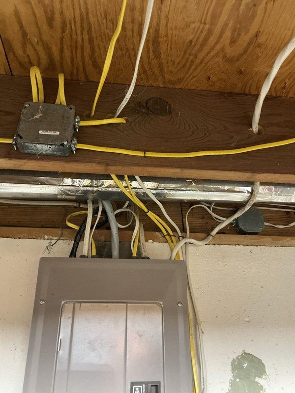 Completed comprehensive electrical system inspection and audit of residential property. Performed thorough examination of main electrical service panel, verifying proper circuit breaker operation, labeling accuracy, and load distribution across all circuits including family room, master bath, dishwasher, guest bedroom, refrigerator/disposal, furnace, sump pump, stove, living room outlets, and smoke detector systems. Inspected attic-level electrical infrastructure, including junction box connections, wire routing through structural framing, and cable management along ceiling joists. Documented existing wiring conditions, noting yellow-jacketed cables, white conductors, and gray service wires properly secured to wooden beams and plywood sheathing. Verified electrical panel interior components, main breaker specifications, and circuit identification systems are functioning as designed with appropriate safety labeling in place.