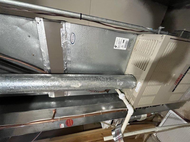 Responded to no cooling complaint on residential split system with frozen evaporator coil. Upon arrival, found unit had been shut off per instructions with fan left running to facilitate defrost. Inspected air handler and evaporator coil assembly in basement location, confirmed ice buildup had cleared. Evaluated system airflow, refrigerant lines, and condensate drainage. Checked filter condition, verified proper operation of blower motor and fan speeds. Inspected ductwork connections and insulation integrity. System components including copper refrigerant lines, PVC condensate piping, and drain pan were examined for proper installation and function. Unit restored to normal cooling operation after thorough inspection and verification of all mechanical components.