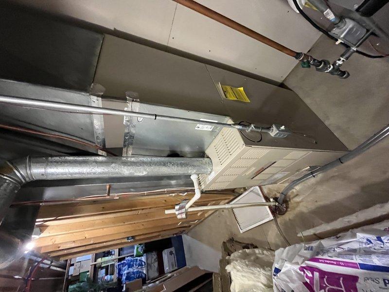 Responded to no cooling complaint on residential split system with frozen evaporator coil. Upon arrival, found unit had been shut off per instructions with fan left running to facilitate defrost. Inspected air handler and evaporator coil assembly in basement location, confirmed ice buildup had cleared. Evaluated system airflow, refrigerant lines, and condensate drainage. Checked filter condition, verified proper operation of blower motor and fan speeds. Inspected ductwork connections and insulation integrity. System components including copper refrigerant lines, PVC condensate piping, and drain pan were examined for proper installation and function. Unit restored to normal cooling operation after thorough inspection and verification of all mechanical components.