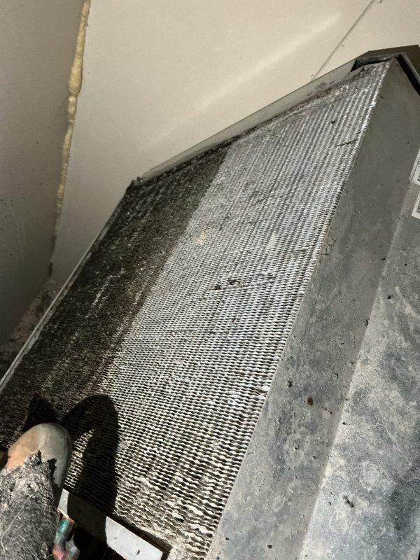 Responded to no-cool call with reported smell of smoke from vents and ice formation on refrigerant lines. Upon arrival, found 10+ year old ground-level unit with severely corroded copper refrigerant lines and fittings showing heavy oxidation and deterioration at connection points. Evaporator coil exhibited substantial buildup of dust and debris accumulation, significantly restricting airflow and reducing system efficiency. Ice formation on both indoor and outdoor refrigerant lines confirmed restricted airflow causing coil to freeze. System had been shut down by occupant with fan left running prior to arrival. Documented extensive corrosion damage to refrigerant tubing and connections, as well as heavily contaminated evaporator coil requiring immediate attention. Provided assessment and repair recommendations to restore proper system operation and prevent further damage.