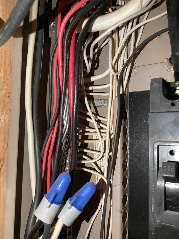 Completed comprehensive electrical inspection of residential service panel and distribution system. Examined main electrical panel housing with standby generator interconnection labeling, verifying proper warning signage and access panel integrity. Inspected internal wiring configuration including multiple circuit conductors (red, black, white, and gray cables), verified proper wire bundling and organization, and confirmed secure wire nut connections on neutral conductors within the distribution box.