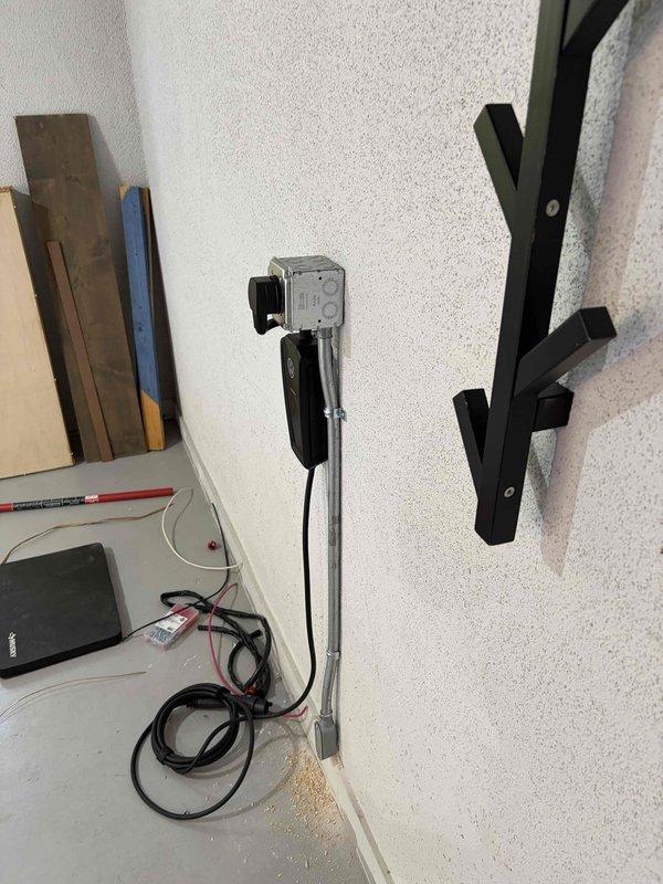 Completed installation of electric vehicle charging station including electrical panel modifications and circuit breaker installation. Mounted charging equipment on interior wall, ran necessary wiring from main service panel, and installed dedicated circuit protection to support the EV charger load requirements per manufacturer specifications and local electrical code.