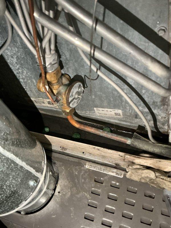Responded to water leak complaint from basement HVAC unit. Upon arrival, inspected interior mechanical components and identified active leak originating from oxidized copper piping and brass valve assembly connections. Found deteriorated pipe fittings with visible corrosion and compromised seals at connection points near heat exchanger assembly. Documented existing conditions showing aged copper tubing with significant oxidation, refrigerant lines, and finned heat exchanger component. Advised customer of findings and recommended system shutdown to prevent further water damage until repairs could be completed.