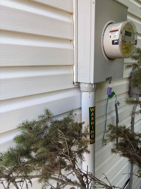 Conducted on-site assessment for new electrical panel installation at residential property. Documented existing exterior electrical infrastructure, including current meter base mounted on white vinyl siding with white PVC conduit system. Evaluated service entrance configuration and accessibility for panel upgrade work. Vegetation around foundation and service entrance area noted for clearance considerations during installation phase.