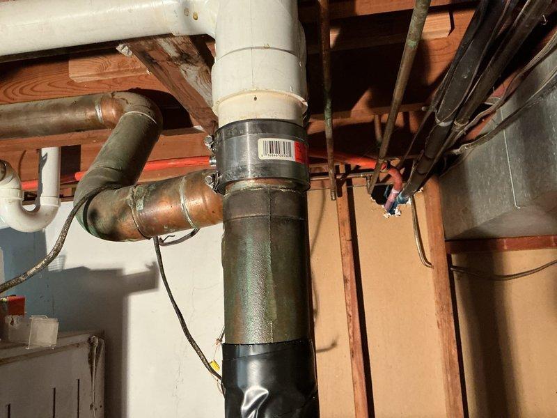 Responded to basement sewer line concern and performed inspection of downspout drainage system. Identified and replaced defective coupling connection between white PVC drain pipe and existing cast iron sewer line. Installed new flexible rubber coupling with stainless steel clamps to ensure proper seal and prevent future leakage. Verified all connections are secure and system is draining properly.