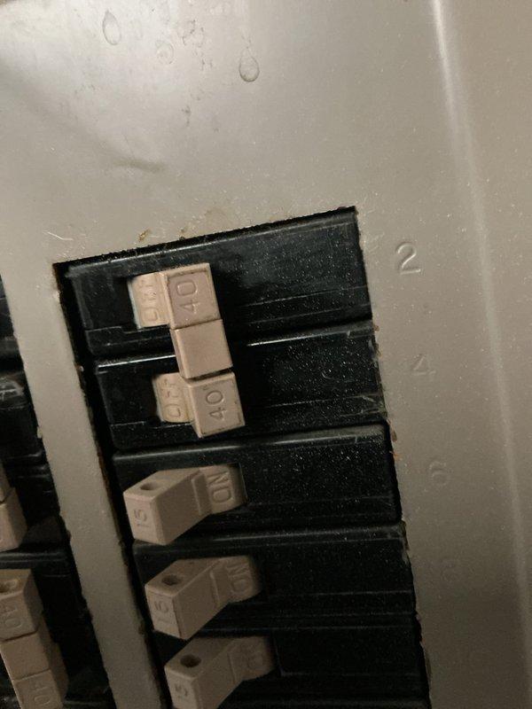 Responded to no-cooling complaint on 10+ year old residential AC unit that had tripped the electrical breaker. Upon arrival, found outdoor condensing unit in side yard location had caused breaker to trip due to electrical overload condition. Inspected circuit breaker panel and confirmed tripped breaker, verified proper breaker sizing for equipment. Examined outdoor unit positioned on concrete pad with conduit and electrical connections along exterior wall. Diagnosed cause of breaker trip and cooling failure, documented equipment condition with photos of both the outdoor unit installation and affected breaker panel. Advised customer to keep system off until repairs could be completed to prevent further electrical issues and potential equipment damage.