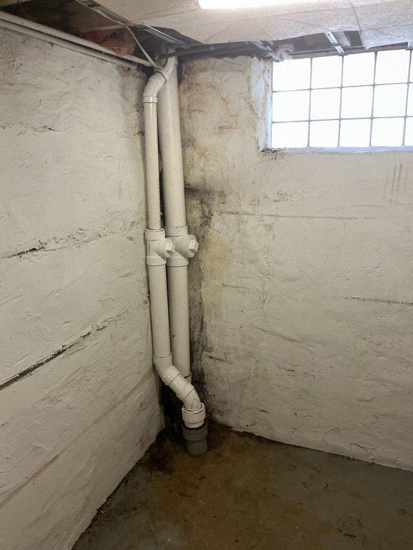 Installed new white PVC drainage piping system in basement utility area, running vertical waste lines along masonry wall with proper fittings and cleanout access points. All pipes were securely mounted and connected with elbow joints for directional transitions, ensuring proper drainage flow in accordance with plumbing code requirements.