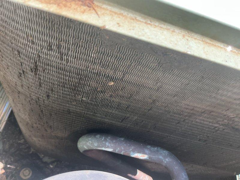 Responded to no cooling complaint on 15-year-old AC system with indoor unit running but outdoor unit not operating. Upon arrival, found outdoor condensing unit not running despite customer's previous breaker reset attempt. Performed diagnostic testing and measured amperage draw at 19.14 amps using digital clamp meter. Inspected outdoor coil and found significant dirt, debris, and possible mold accumulation on condenser fins, along with rust streaks on housing indicating extended environmental exposure and lack of maintenance. Outdoor unit failure attributed to compromised airflow from heavily soiled coil and potential electrical or mechanical component failure requiring further evaluation.