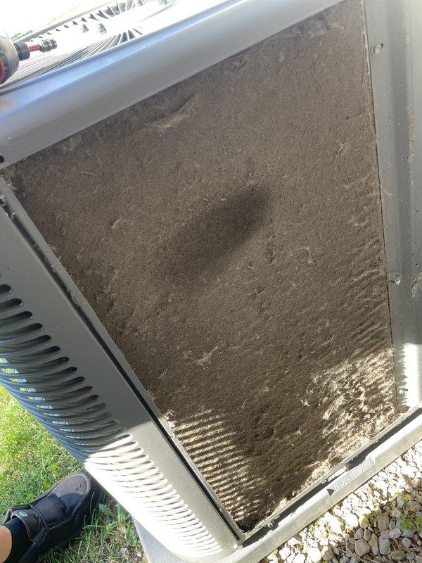 Responded to no cooling complaint on 10-year-old residential air conditioning system. Upon inspection, found outdoor condenser unit's intake filter completely blocked with heavy accumulation of dirt, dust, and debris, severely restricting airflow to the system. Removed and cleaned clogged filter, restoring proper airflow to condenser unit. Verified thermostat was set to cooling mode and confirmed system returned to normal operation with cold air delivery restored.