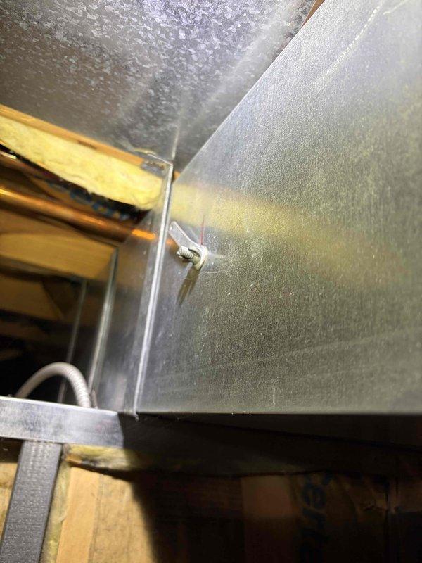 Responded to service call regarding Trane XL A50 thermostat displaying air cleaner mode and reports of insufficient airflow from multiple supply vents. Upon inspection, accessed attic space and examined HVAC ductwork system serving 10-year-old unit located at side of house. Investigated duct runs and plenum connections to identify potential airflow restrictions or disconnected ductwork that could cause reduced air delivery to affected rooms. Verified duct support straps and connections at main trunk line and branch ducts. Assessed thermostat settings and air cleaner mode functionality to determine if IAQ system was operating correctly or if control settings required adjustment. Documented ductwork configuration and condition with photos showing plenum assembly, metal duct installation, support brackets, and insulation placement in attic space.