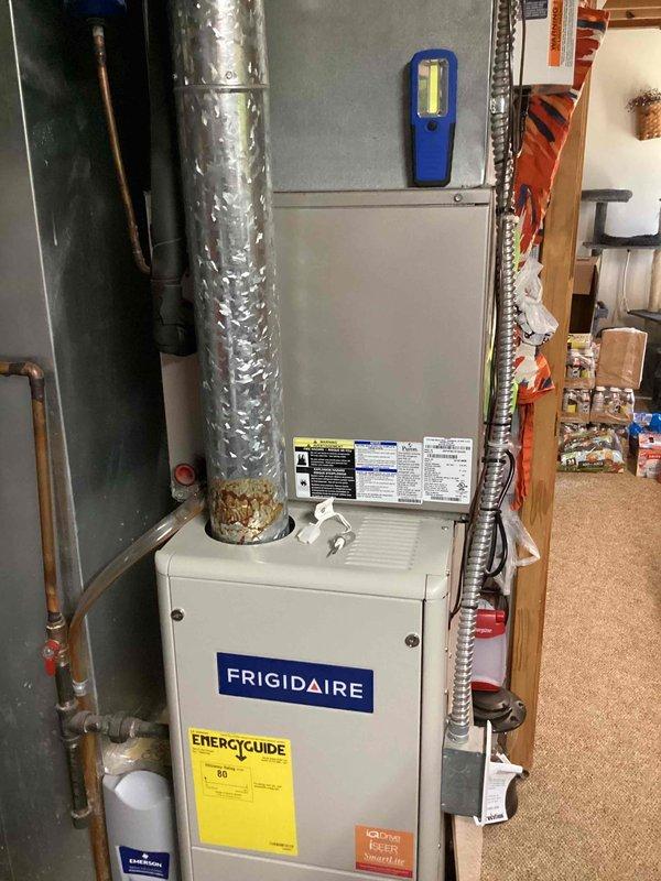 Responded to no cooling complaint affecting entire home with 12-year-old Frigidaire HVAC system. Upon arrival, performed comprehensive system diagnostics on indoor air handler unit located in basement utility area. Inspected furnace cabinet, ductwork connections, refrigerant lines, and electrical components. Noted visible corrosion at base of metallic supply duct connection point. Verified proper airflow through system, checked thermostat communication, and tested capacitor functionality. Documented equipment condition with photos showing installation configuration, manufacturer labels, and areas of concern including rust formation on ductwork interface. Confirmed best contact number for follow-up communication.