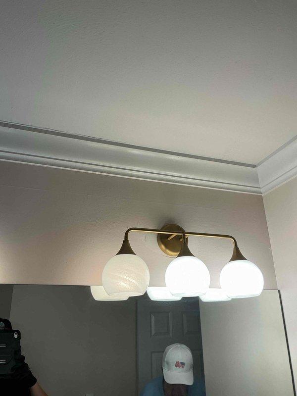 Responded to service call for flickering lights in bathroom vanity fixture. Upon arrival, diagnosed six-light brass fixture with only four operational bulbs after customer broke two during troubleshooting attempts. Tested electrical connections and determined flickering was caused by loose bulbs and improper contact. Advised customer that replacement bulbs are not stocked on service vehicle and must be provided by homeowner for this decorative fixture type with frosted globe shades. Verified proper voltage and confirmed fixture wiring and connections were secure with no electrical faults present.