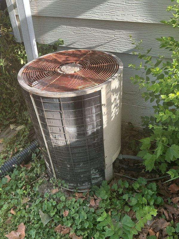 Responded to no-cooling complaint on 10+ year old residential AC system. Upon arrival, performed diagnostic evaluation of outdoor condenser unit showing significant weathering and rust deterioration on fan grille, and inspected indoor Sinclair furnace with air handler components in basement. Documented equipment condition through photographs revealing aging outdoor unit with corroded top grille assembly and indoor HVAC system configuration. System blowing air throughout home but failing to provide adequate cooling to living spaces.