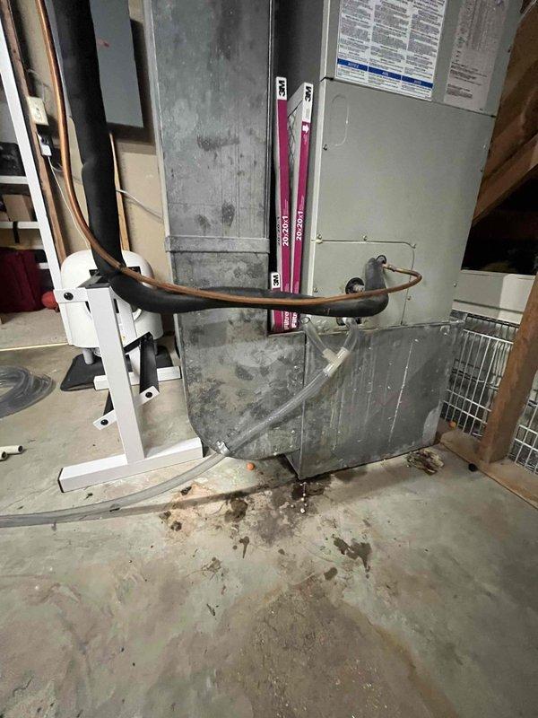 Responded to report of water leaking from basement air conditioning system. Upon inspection, discovered excessive debris and sediment buildup in the condensate drain line causing blockage and water overflow. Cleared the obstruction from the drain system, flushed the condensate line, and verified proper drainage flow. Inspected the 10-year-old air handler unit and associated refrigerant lines for any additional issues; all components found to be functioning properly after drain line service.