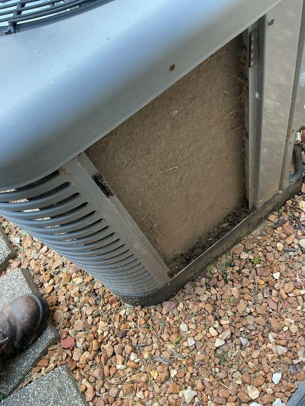Responded to service call for outdoor AC unit experiencing intermittent banging noise. Upon arrival, unit had been shut off by homeowner as a safety precaution. Performed comprehensive inspection of condenser unit and discovered severely contaminated base filter/panel with significant dirt accumulation and discoloration. Removed access panel to assess internal components and filter condition. Documented equipment condition with photos showing heavy debris buildup on filtration material and weathered components. The contaminated filter and debris accumulation were identified as likely contributors to the reported banging noise, as restricted airflow can cause pressure imbalances and component vibration within the system.