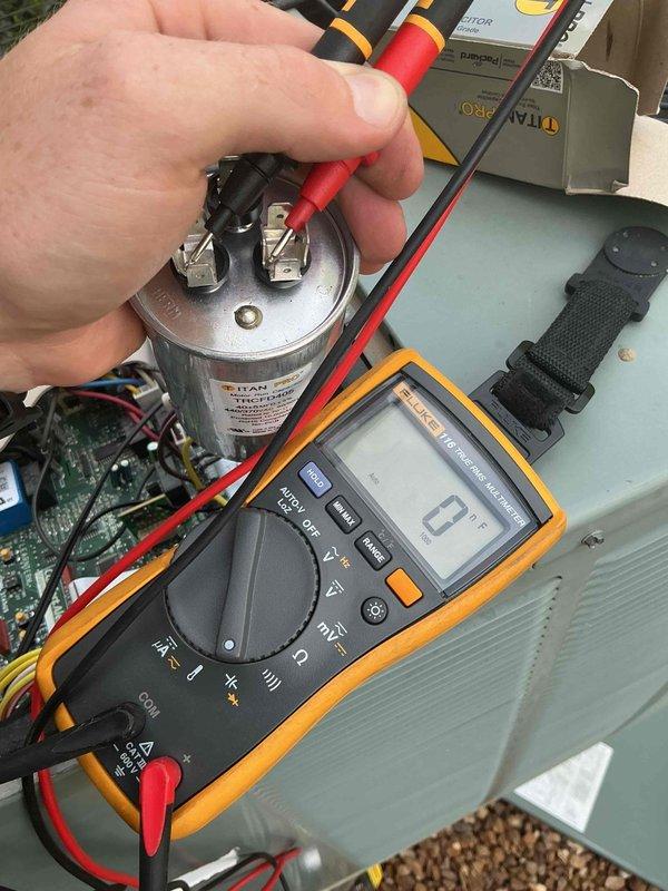 Responded to no cooling call on 10-year-old residential unit located on side of house. Upon arrival, performed diagnostic testing which revealed failed dual run capacitor. Tested capacitor with multimeter confirming zero microfarad reading, indicating complete failure. Measured supply air temperature at interior register reading 56.5°F, confirming lack of cooling. Replaced defective capacitor with new OEM equivalent, restored system to normal operation, and verified proper cooling cycle.