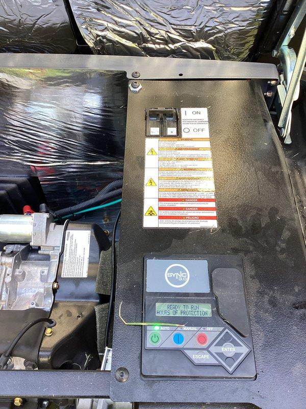 Performed routine preventive maintenance on commercial standby generator equipped with Sync 3.0 control system. Upon arrival, verified generator status displayed "READY TO RUN" with battery inspection advisory on LCD interface. Conducted comprehensive inspection of control panel functions, testing AUTO, MANUAL, and OFF mode selections to ensure proper operational capability. Examined all safety interlocks and warning systems, confirming bypass protection features were functioning correctly. Inspected battery connections and charging system, noting maintenance alert on display panel. Checked all electrical connections, control wiring, and associated mechanical components including pump assembly and corrugated conduit routing. Verified proper operation of ON/OFF switch and navigation controls. Cleaned control panel face and surrounding equipment housing. Reviewed all warning labels and safety placards for visibility and compliance. Discussed available preventive maintenance packages with