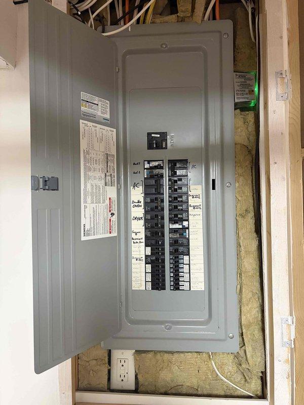 Investigated reported electrical outlet issue at residential property. Upon arrival, conducted visual inspection and testing of the outlet in question. Examined electrical panel to verify proper circuit breaker operation and circuit labeling. Inspected wiring connections at panel box and confirmed all breakers were functioning correctly. Tested outlet for proper voltage, grounding, and polarity. Documented existing electrical panel configuration showing dual columns of circuit breakers with handwritten circuit identification labels. All circuits appeared properly labeled and organized. No immediate electrical hazards or code violations observed during inspection. Outlet tested within normal operating parameters with no signs of overheating, loose connections, or damage.