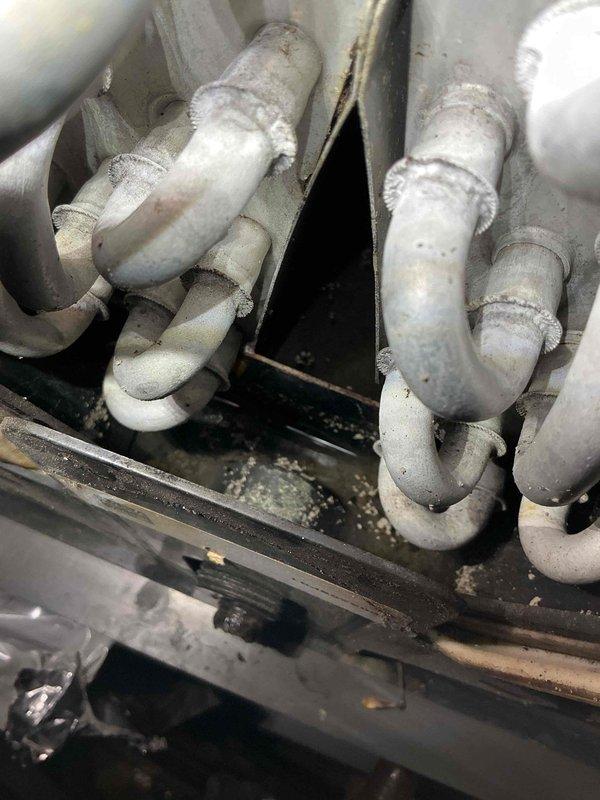 Responded to service call for water pooling from 10-year-old basement unit with reported strange noises. Upon inspection, discovered severely frozen evaporator coil and refrigerant lines with heavy ice and frost buildup on copper piping and insulation, indicating restricted airflow or low refrigerant charge. Documented frozen components with photos showing crystalline ice accumulation on parallel refrigerant lines and surrounding mechanical assemblies. Advised customer on findings and recommended system evaluation to determine root cause of freezing condition, which was causing condensate overflow and water pooling issue.