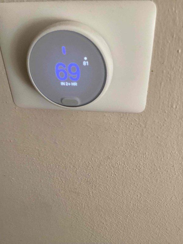 Responded to no cooling complaint following recent solar panel installation. Upon arrival, found thermostat displaying 81°F actual temperature while set to 69°F with a 2+ hour delay indicated. Performed diagnostic evaluation of 10+ year old outdoor condensing unit located on side of house. Unit showed significant age-related deterioration including rust staining on fan guard and top panel, indicating extended outdoor exposure. Conducted system assessment to determine if cooling issue was related to solar electrical work or equipment failure. Verified unit operation, checked electrical connections, and assessed refrigerant system performance. Documented equipment condition with photos showing thermostat readings and exterior unit condition for service records.